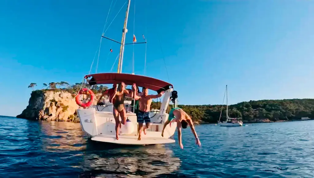 Amigos saltando del barco alquilado en mallorca